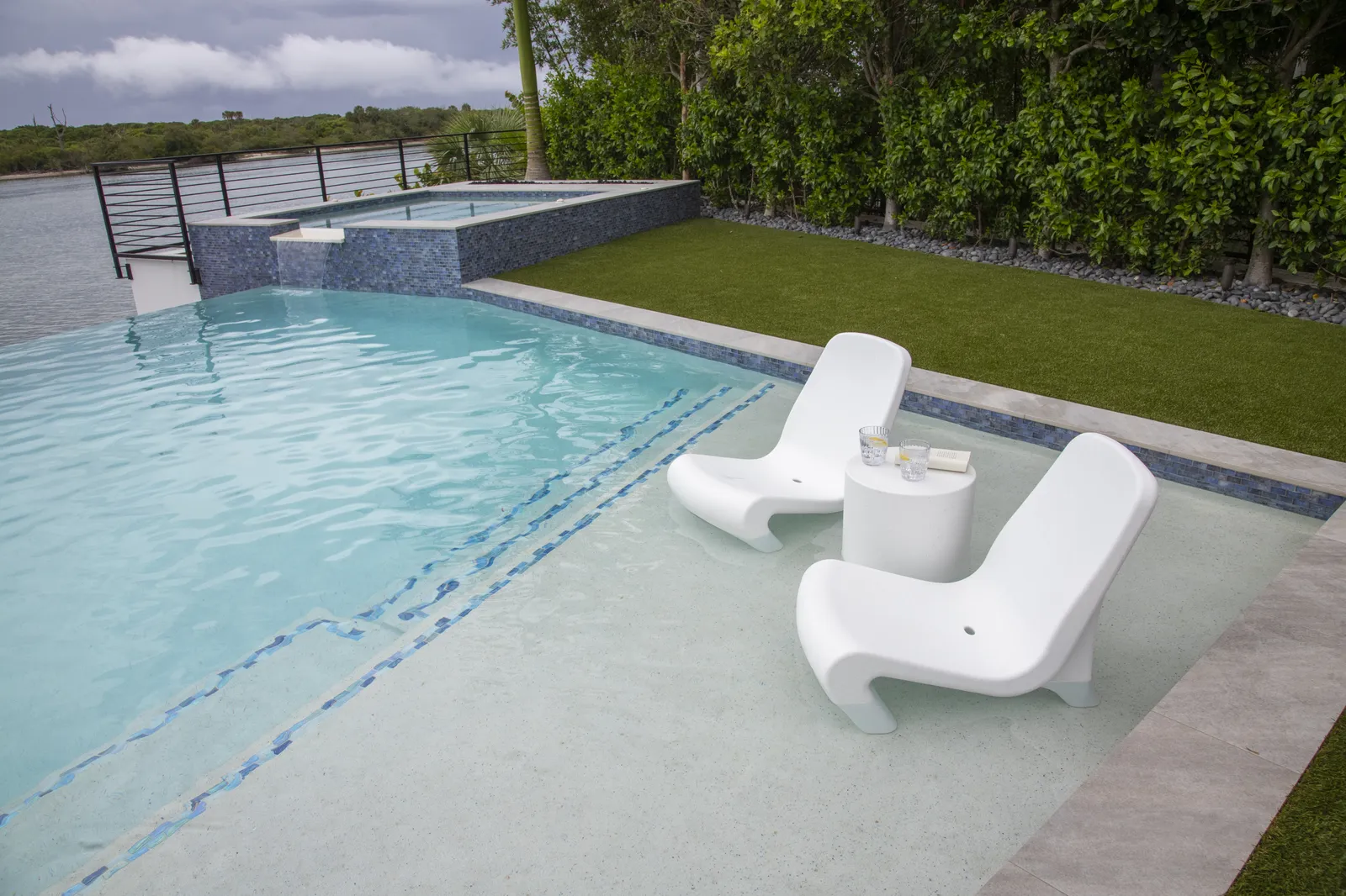 Tenjam Freelo in-pool chairs and table on a pool tanning ledge